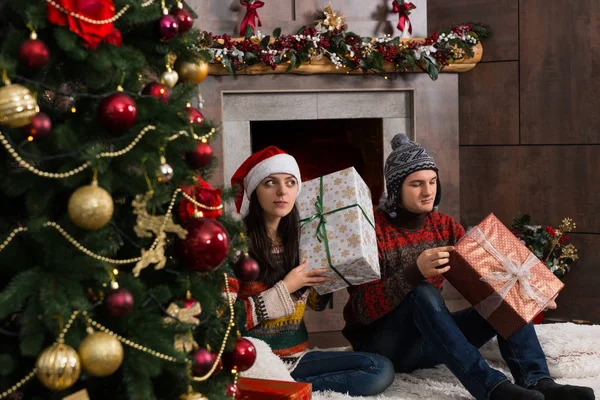 Linda pareja joven adivinando en sus regalos de Navidad sosteniendo una caja —  Fotos de Stock