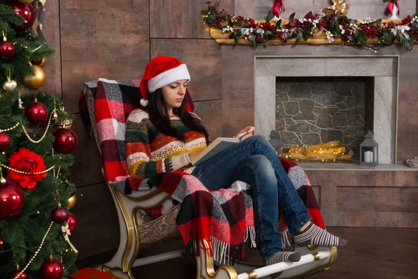 Beautiful woman in funny Christmas hat reading while sitting in — Stock Photo, Image