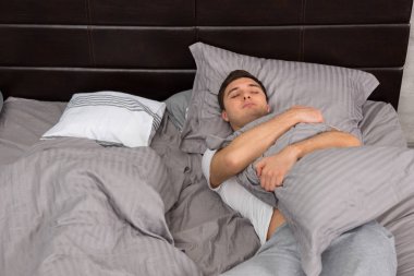 Genç erkek pijama yalnız battaniye ve sarılmak uyku yorgun