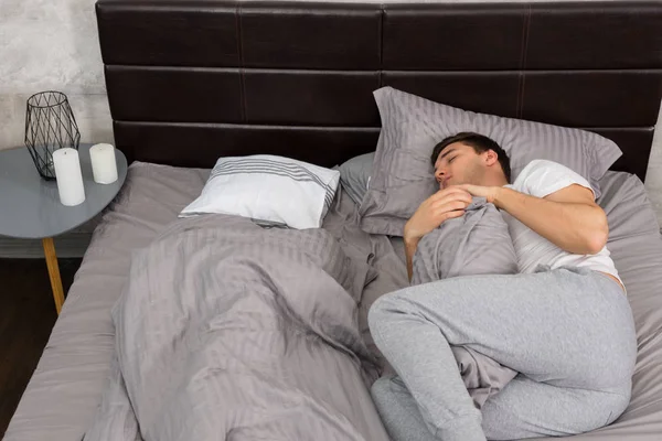 Bello stanco maschio in pigiama dormire da solo senza coperta e — Foto Stock