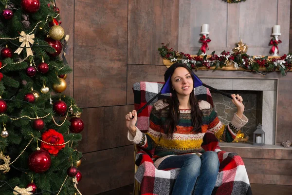 Attraktive lächelnde Frau mit lustig gestricktem nordischen Hut sitzt in — Stockfoto