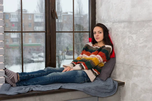 Jeune femme réfléchie couchée sur les oreillers sur les fenêtres — Photo