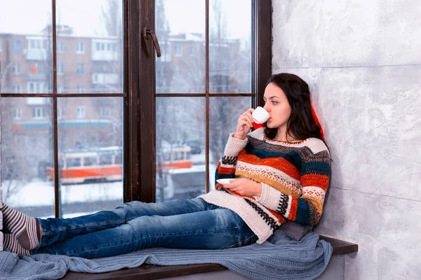 Mooie jongedame liggen op de kussens op de windowsil — Stockfoto