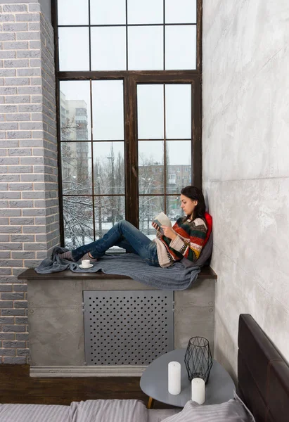 Junge schöne Frau auf der Fensterbank liegend mit Kissen und B — Stockfoto