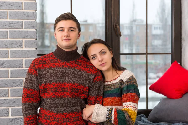 Young beautiful couple in warm knitted sweaters looking at the c — Stock Photo, Image