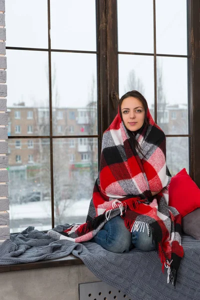 Mooie jongedame gewikkeld in een deken zittend op de — Stockfoto
