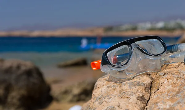 Máscara subaquática e tubo deitado na rocha na praia em um sol — Fotografia de Stock