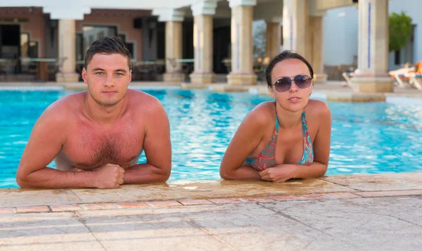 Young suntanned couple relaxing in a swimming pool — Stock Photo, Image