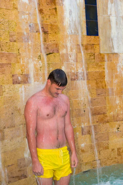 Jovem homem bonito tomando banho ao ar livre como uma cachoeira no — Fotografia de Stock