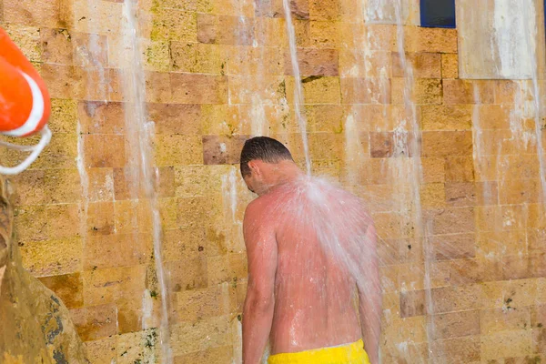 Hombre guapo tomando una ducha al aire libre como una cascada en el hotel — Foto de Stock