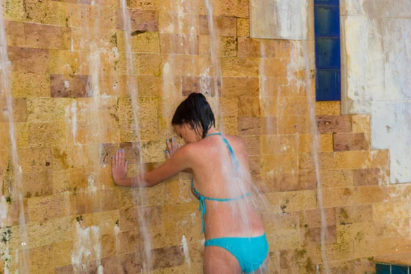 Young woman wearing turquoise swimsuit taking outdoor shower lik — Stock Photo, Image