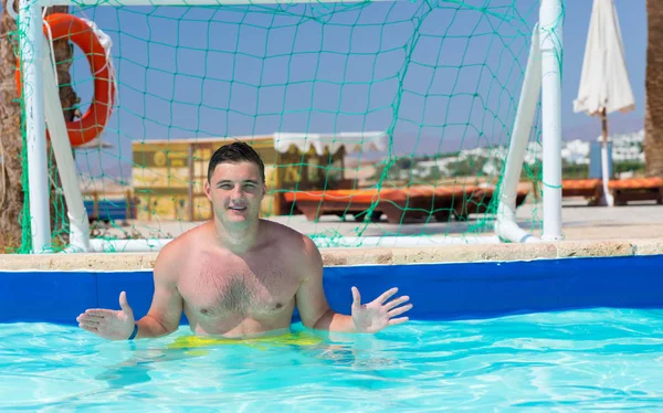 Bonito homem de pé no portão na piscina jogando pólo aquático — Fotografia de Stock