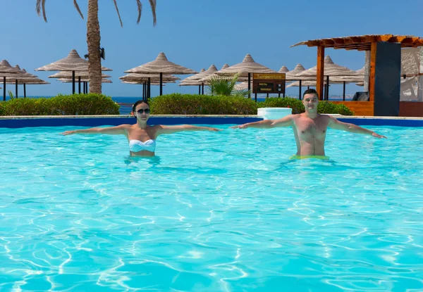 Feliz pareja joven haciendo aqua fitness en la piscina — Foto de Stock