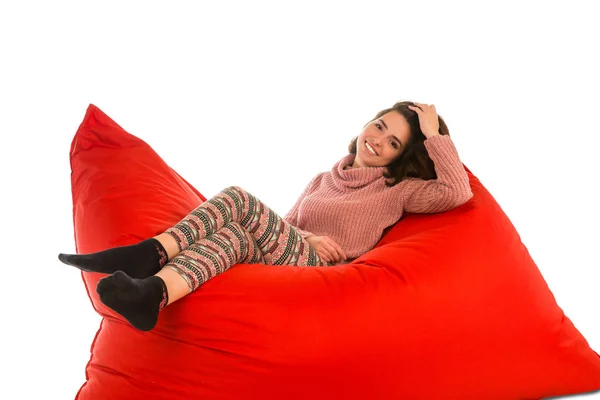 Mignonne jeune femme couché sur rouge carré en forme de canapé de sac de haricot chaise i — Photo