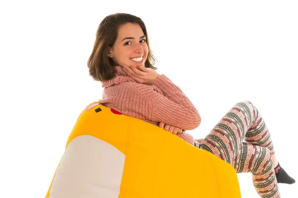Vista lateral de una mujer linda sonriente sentada en una silla de frijoles amarillos —  Fotos de Stock