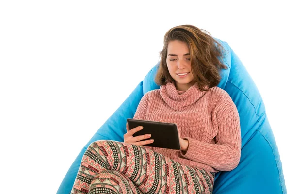 Jovem mulher sentada na cadeira beanbag azul e segurando um tablet i — Fotografia de Stock