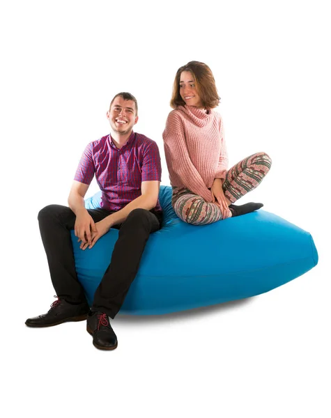 Junger lächelnder Mann und Frau sitzen isoliert auf blauem Sitzsack-Sofa — Stockfoto