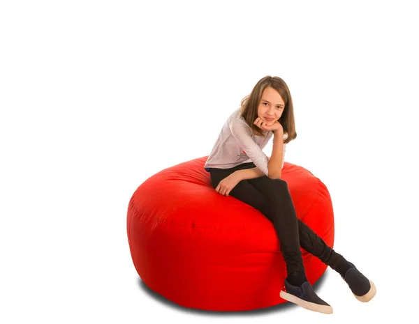 Menina bonito jovem sentado em forma redonda cadeira beanbag vermelho — Fotografia de Stock