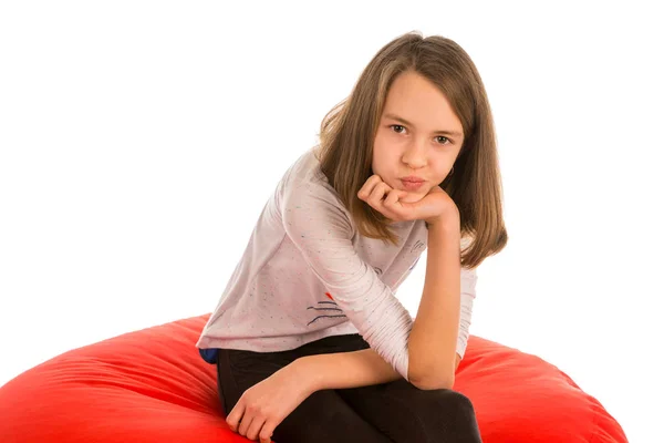 Menina bonito sentado em forma redonda cadeira beanbag vermelho — Fotografia de Stock