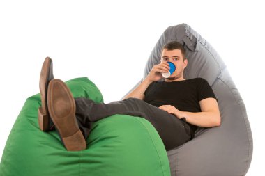 Beanbag sandalye üzerinde yalan ve kahve içme genç adam