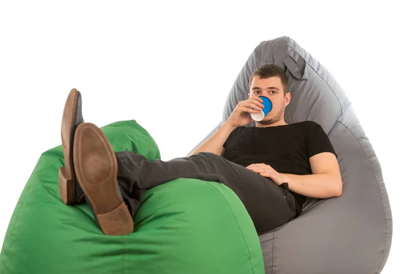 Молодой человек лежит на креслах и пьет кофе — стоковое фото