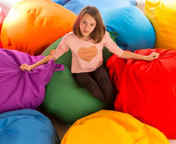 Young happy girl sitting between beanbag chairs — Stock Photo, Image