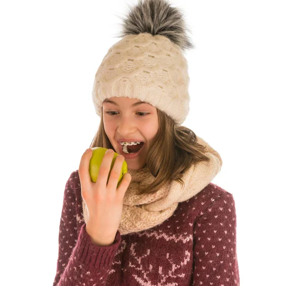 Chica divertida en suéter caliente, sombrero, bufanda y manoplas comiendo una aplicación — Foto de Stock