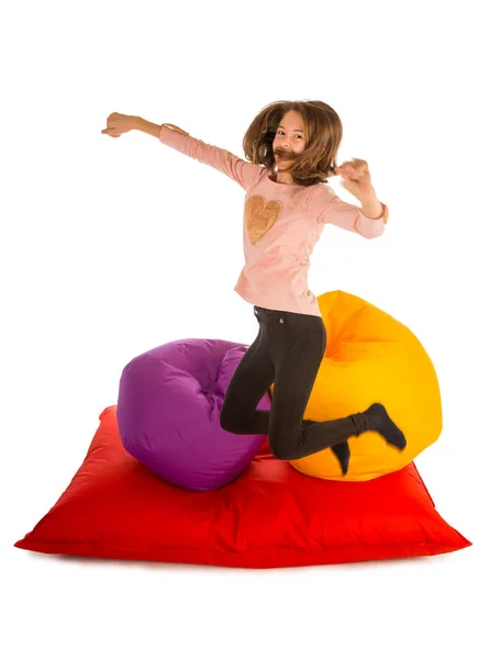 Funny girl jumping near beanbag chairs and beanbag sofa — Stock Photo, Image