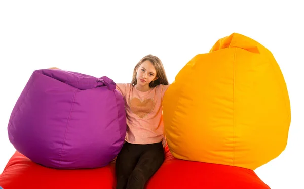 Dívka sedí mezi Pytlové křesla na pohovce červená beanbag — Stock fotografie