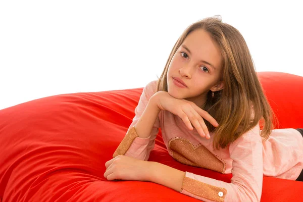 Menina bonita deitada no sofá beanbag vermelho para sala de estar ou outro r — Fotografia de Stock