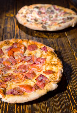 İki farklı pizza çeşitli soslar ve peynir ile