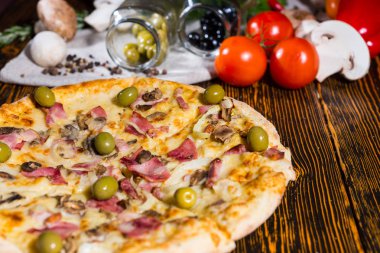 Jambon ve zeytin ahşap masa ve diğer vegeta lezzetli pizza