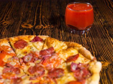 Lezzetli biberli pizza yakınındaki bir bardak domates suyu ile yakın çekim