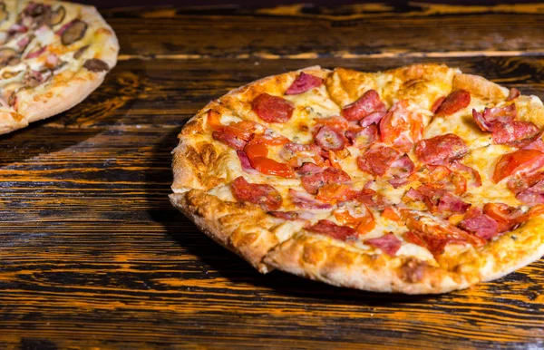 Leckere Pizza mit Schinken, Peperoni, Tomaten und Soße auf hölzernem Ta — Stockfoto