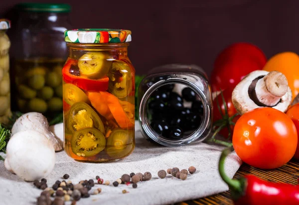 Öppna burken med svarta oliver ligger på en servett nära burkar med inlagda — Stockfoto
