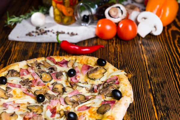Primo piano di gustosa pizza con prosciutto, cipolla, olive sul tavolo di legno — Foto Stock