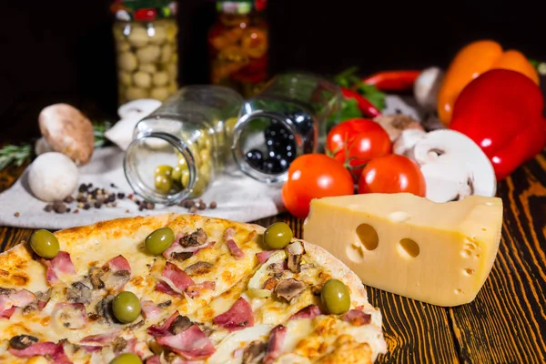 Pizza z oliwkami na drewnianym stole i inne warzywa w ba — Zdjęcie stockowe