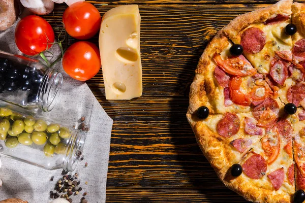 Вид под высоким углом на половину пиццы пепперони с оливками, рядом лежат — стоковое фото