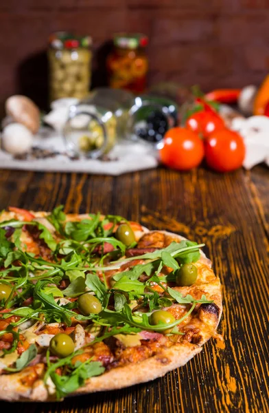 Smaczne pizza z rukolą i oliwki na drewnianym stole i innych ve — Zdjęcie stockowe
