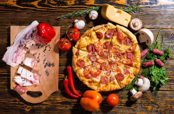 Высокий угол обзора пиццы пепперони на деревянном столе в окружении — стоковое фото