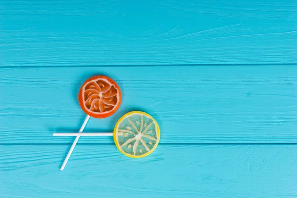 Lutscher als Orange und Zitrone auf türkisfarbenem Holzbrett — Stockfoto