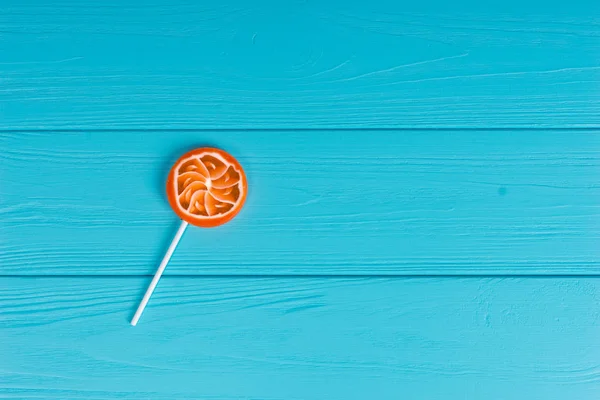 Piruleta como una naranja sobre tabla de madera turquesa —  Fotos de Stock