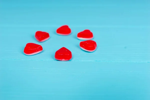 Red candies in the shape of a heart on wooden turquoise table — Stock Photo, Image