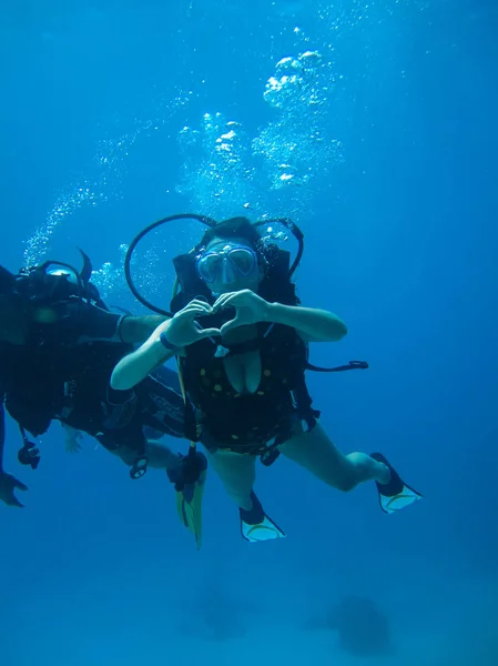 Podwodne strzelać młodej kobiety, nurkowanie i pokazując miłość sygnału — Zdjęcie stockowe