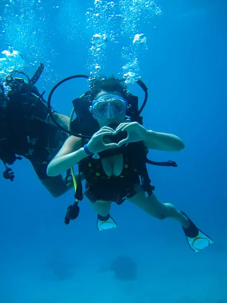 Podvodní natáčení mladé ženy potápění a ukazovat lásku signa — Stock fotografie