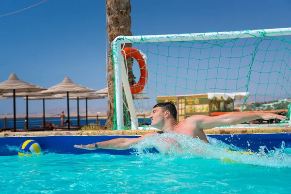 Hombre en acción tratando de atrapar la pelota en la piscina jugando al agua pol — Foto de Stock