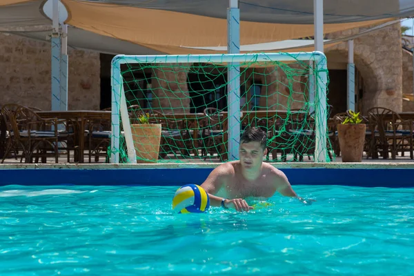 Atlético homem de pé no portão na piscina enquanto joga água po — Fotografia de Stock