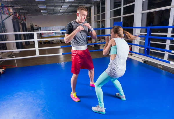 Pareja atlética en ropa deportiva practicando boxeo en boxín regular — Foto de Stock