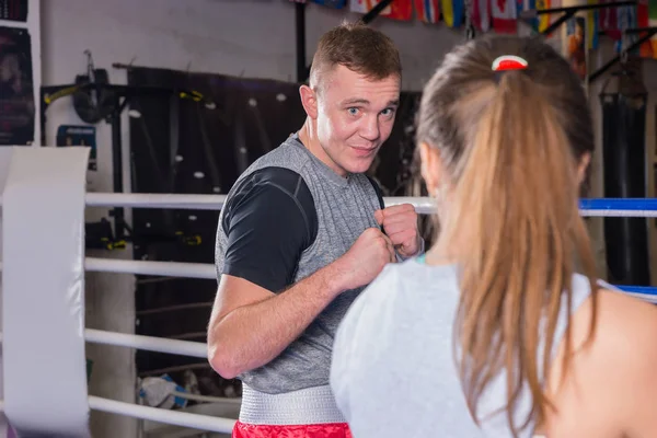 Portrait of young male boxer in sportswear training with female