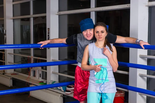 Sporty pair standing near blue corner of a regular boxing ring — Stock Photo, Image